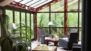 Un invernadero con ventanas grandes, muebles de mimbre y plantas en macetas.