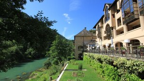 Un hotel junto al río con un sendero en el jardín, asientos al aire libre y vistas al río.