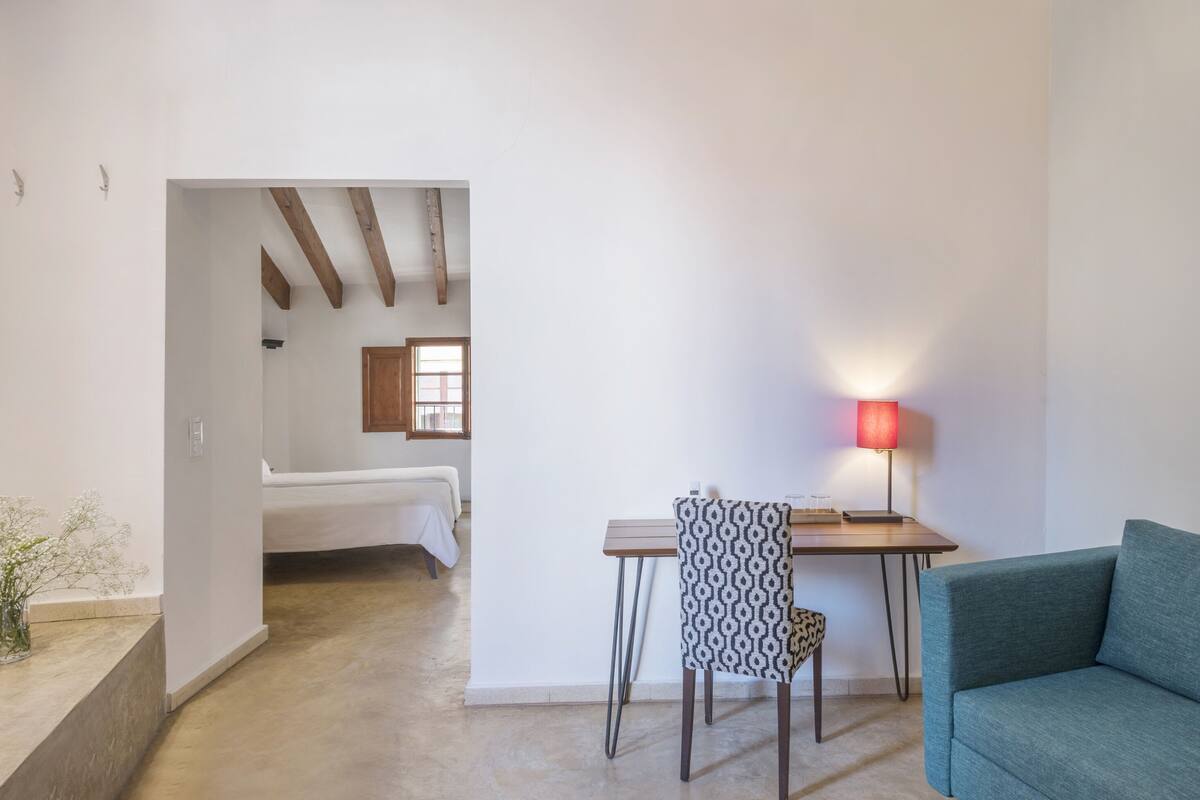 Une pièce comprenant un lit, un bureau avec une chaise, une lampe et un canapé.