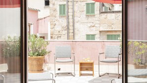 A balcony with two chairs and a small table, a potted plant, and a red umbrella. - Hotel Palau Sa Font (Palma de Mallorca)