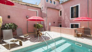 A rooftop pool area with lounge chairs, red umbrellas, and a tiled deck. - Hotel Palau Sa Font (Palma de Mallorca)