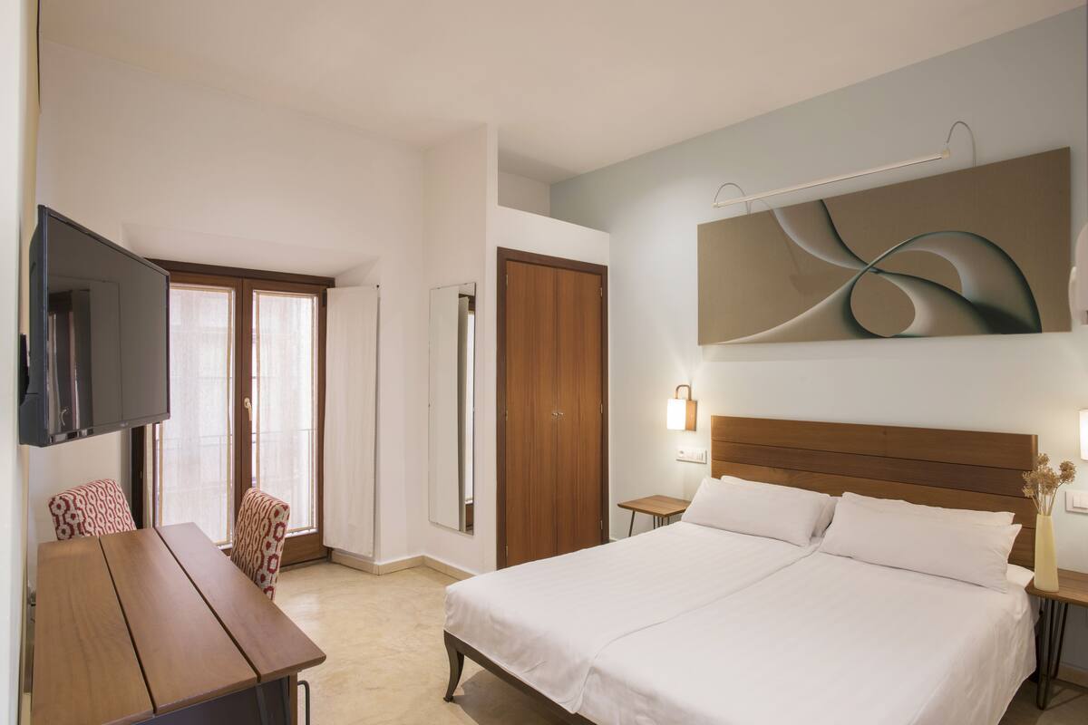 Une chambre d’hôtel avec un grand lit, un bureau, une télévision et une armoire.