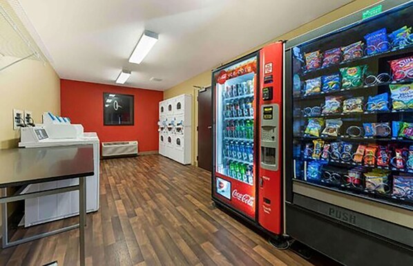 A vending machine area with a Coca-Cola cooler and a push vending machine filled with snacks.