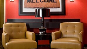 A lobby with two leather armchairs, a welcome sign, and a lamp on a small table.
