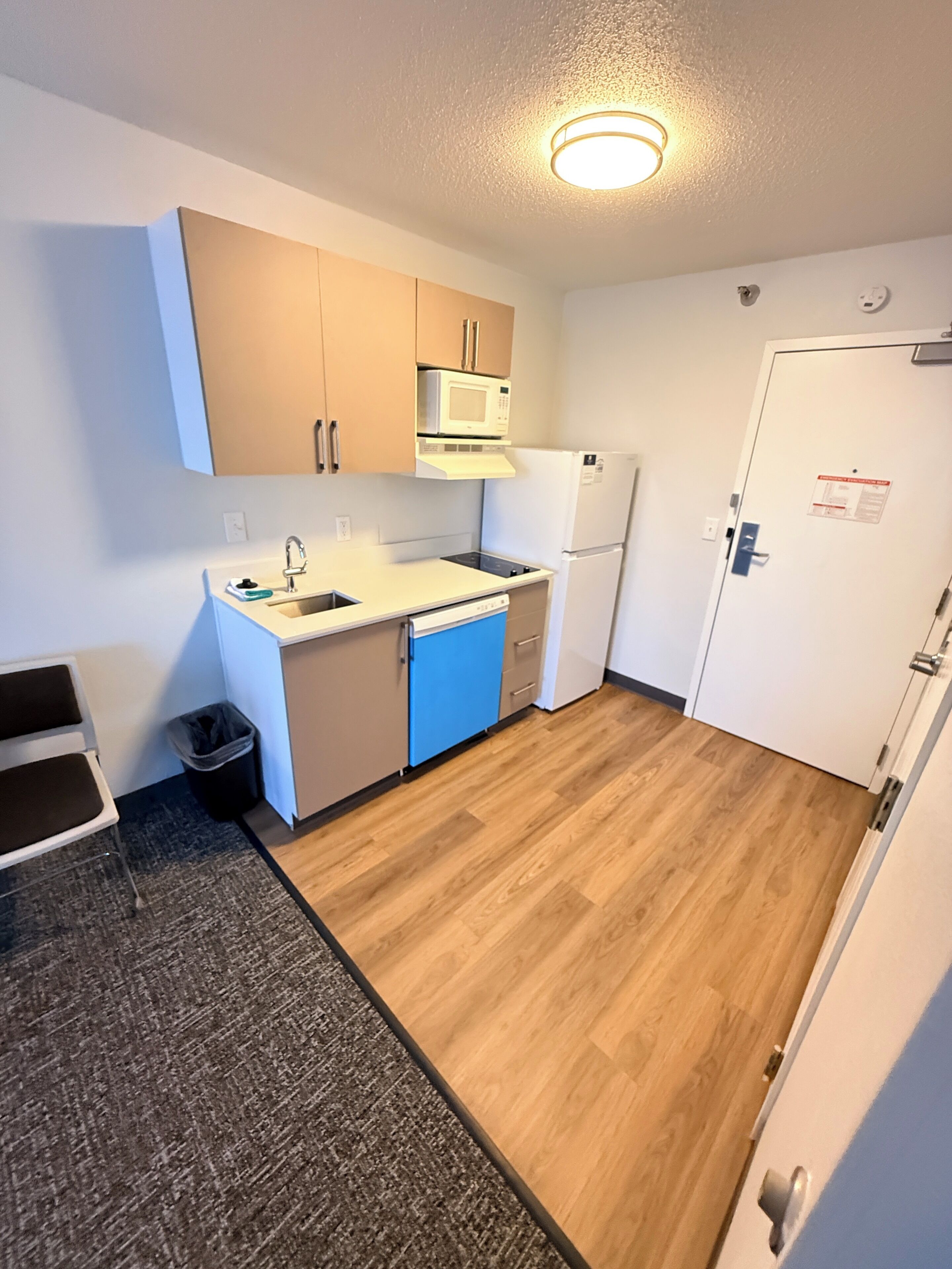 Una cocina compacta con microondas, lavamanos y refrigerador.