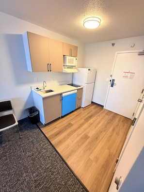 A compact kitchen with a microwave, sink, and refrigerator.