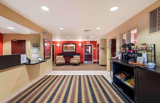 Un hall de hotel con mostrador de recepción, un letrero que dice 'WELCOME', una zona de estar y un mostrador de buffet.