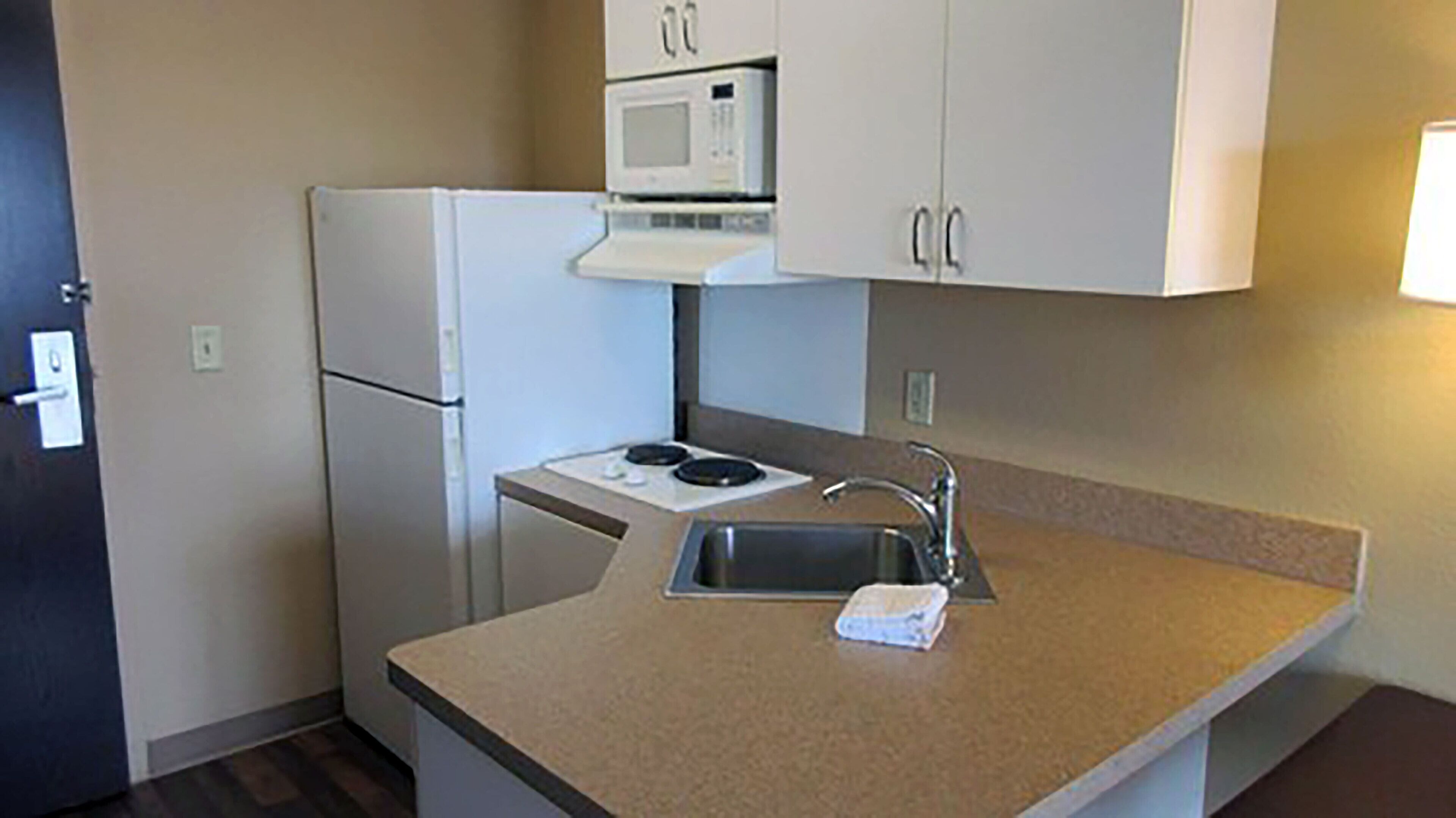 A compact kitchen with a refrigerator, microwave, stove, and sink.