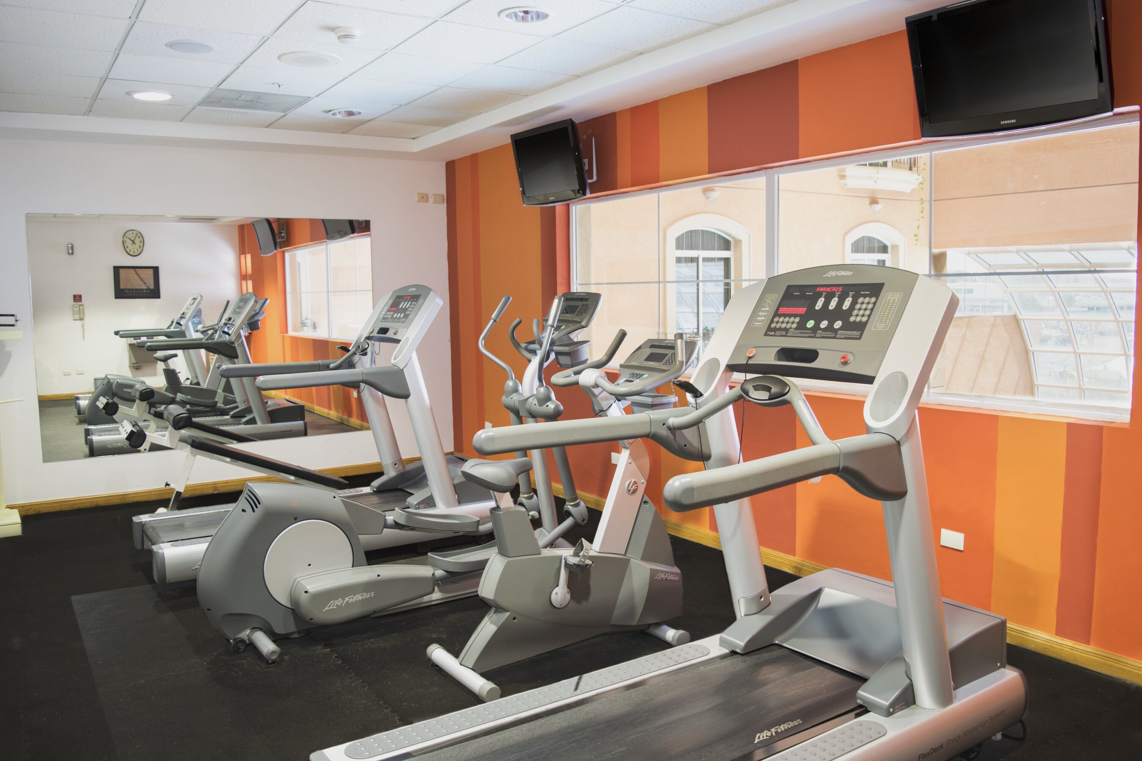 Un gimnasio con cintas de correr y equipo de ejercicio.