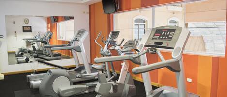 Un gimnasio con cintas de correr y equipo de ejercicio.