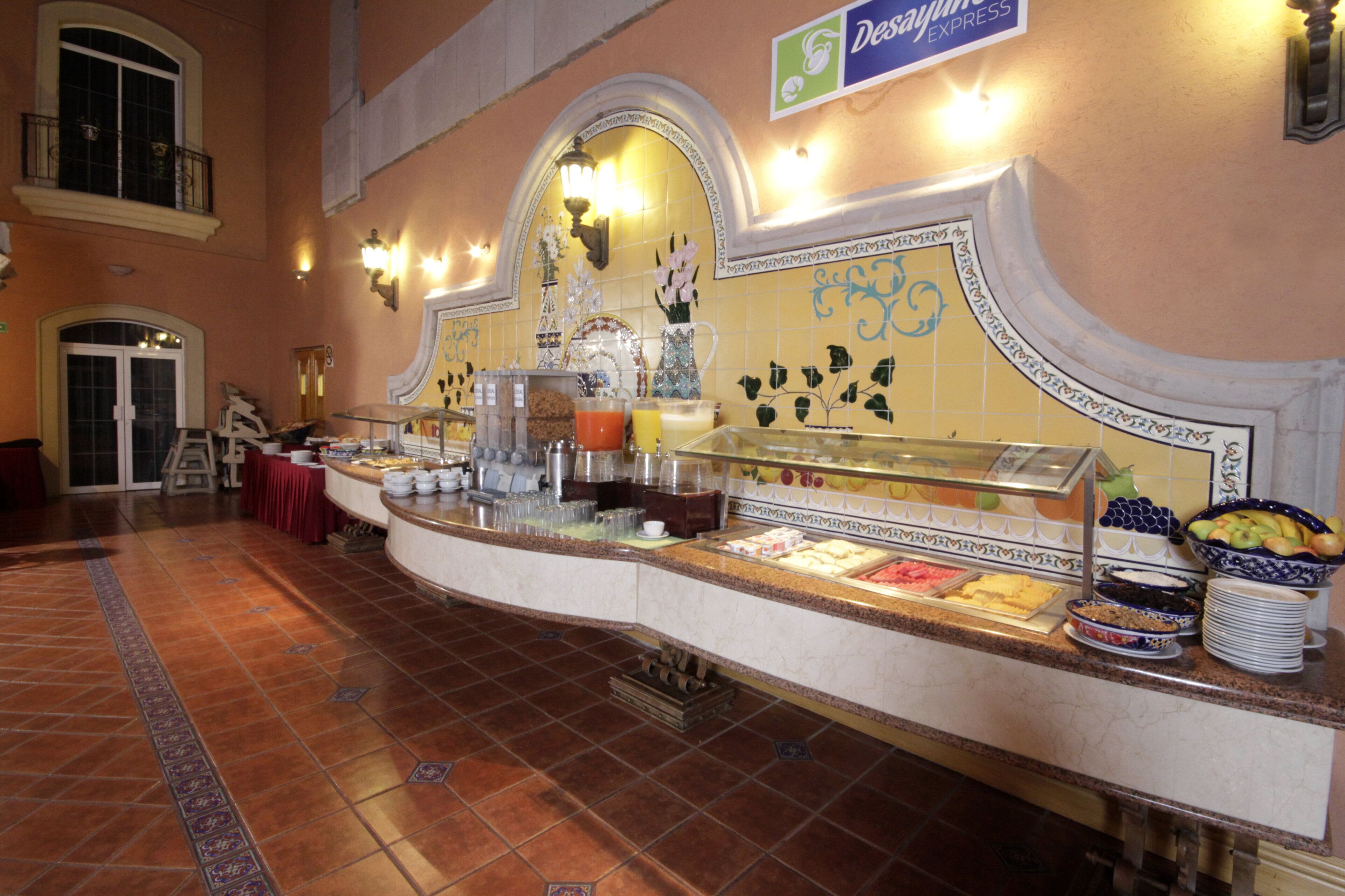 A buffet area with various food options, a reception desk, and a sign for 'Desayune Express'.