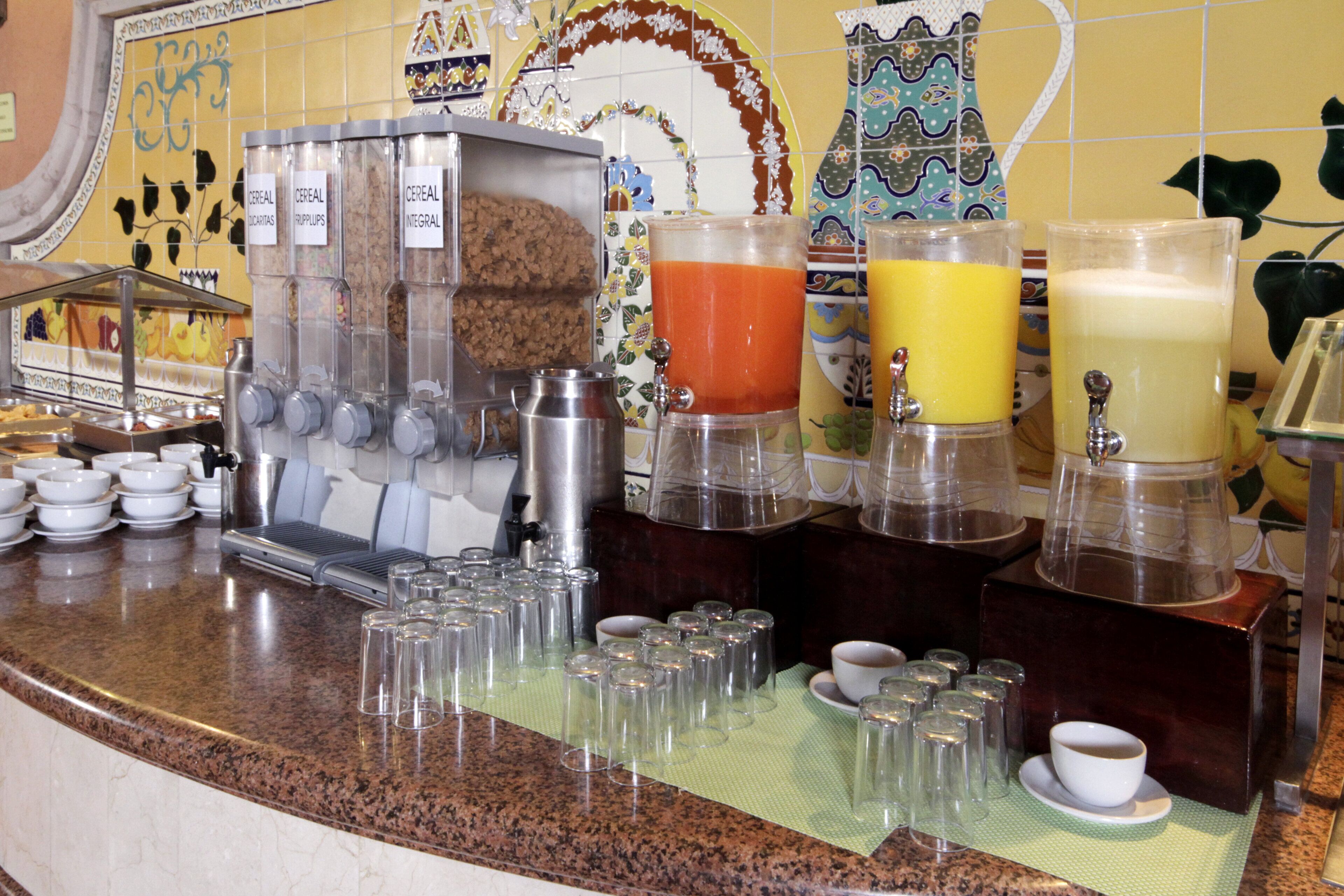 A breakfast bar with various food and drink dispensers, including cereal and juices.