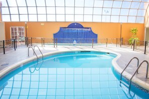 An indoor swimming pool with a tiled edge, a metal railing, and a blue decorative wall in the background. - Holiday Inn Express Guanajuato by IHG (Guanajuato)
