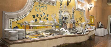 Montaje de bufé con diversas opciones de comida y una pared de azulejos con diseños decorativos.