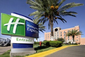A Holiday Inn Express sign with a palm tree and a building in the background. - Holiday Inn Express Guanajuato by IHG (Guanajuato)