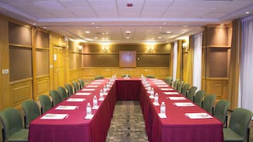 Una sala de conferencias con una larga mesa, sillas y suelo alfombrado.