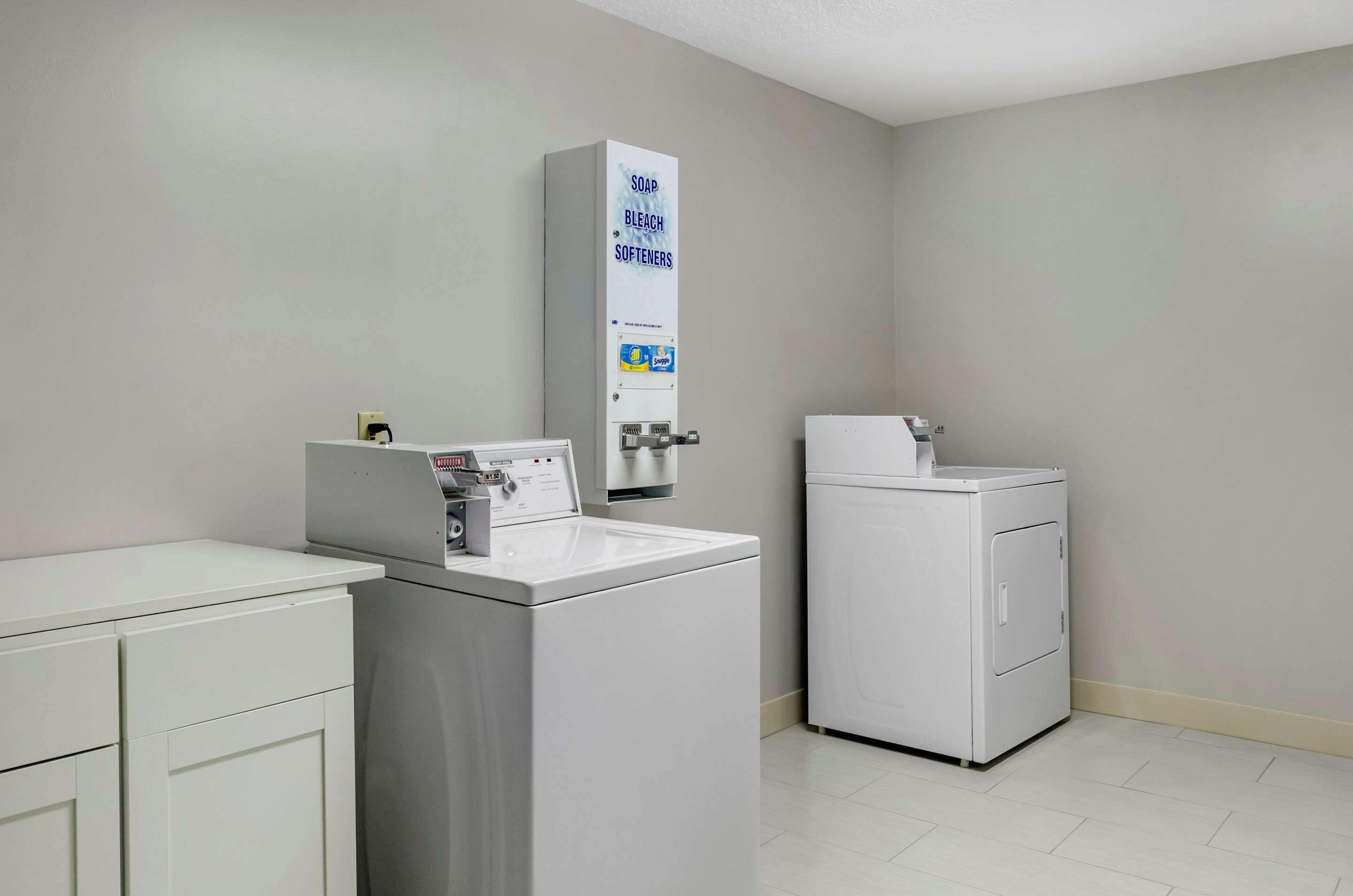 A laundry area with a washing machine, a dryer, and a soap dispenser.