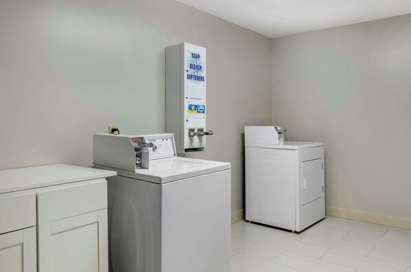 A laundry area with a washing machine, a dryer, and a soap dispenser.