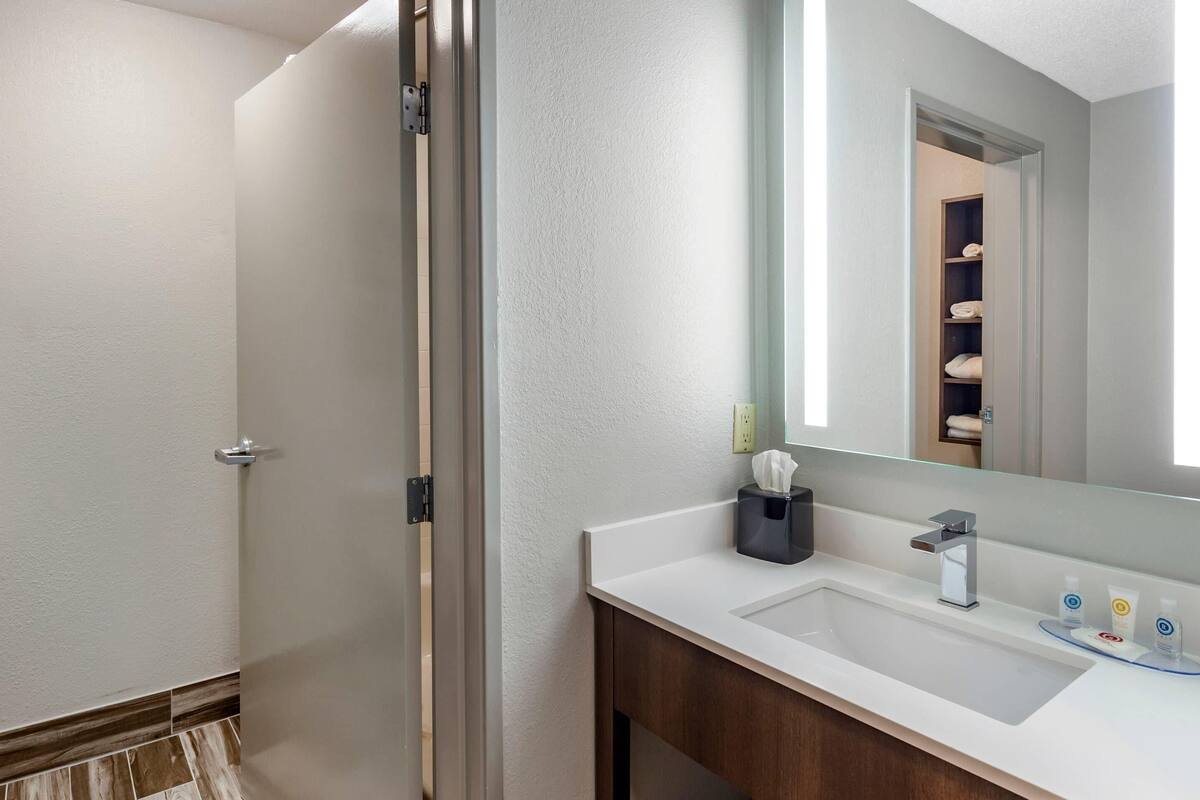 A modern bathroom with a white sink, a mirror, and a shower area.