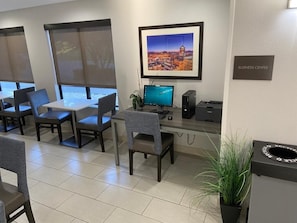 Business center with a long table, computer setup, and printer, perfect for productivity.