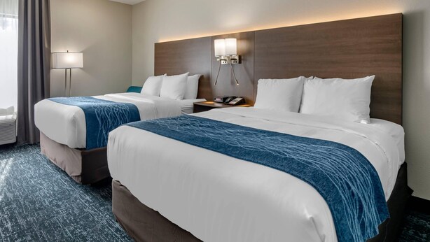 A hotel room with two beds, a nightstand with a phone, a lamp, and a wall-mounted light fixture. - Comfort Inn & Suites Troutville-Roanoke North (Troutville)