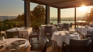En restaurang med bord dukade för middag, stora fönster och utsikt över landskapet.