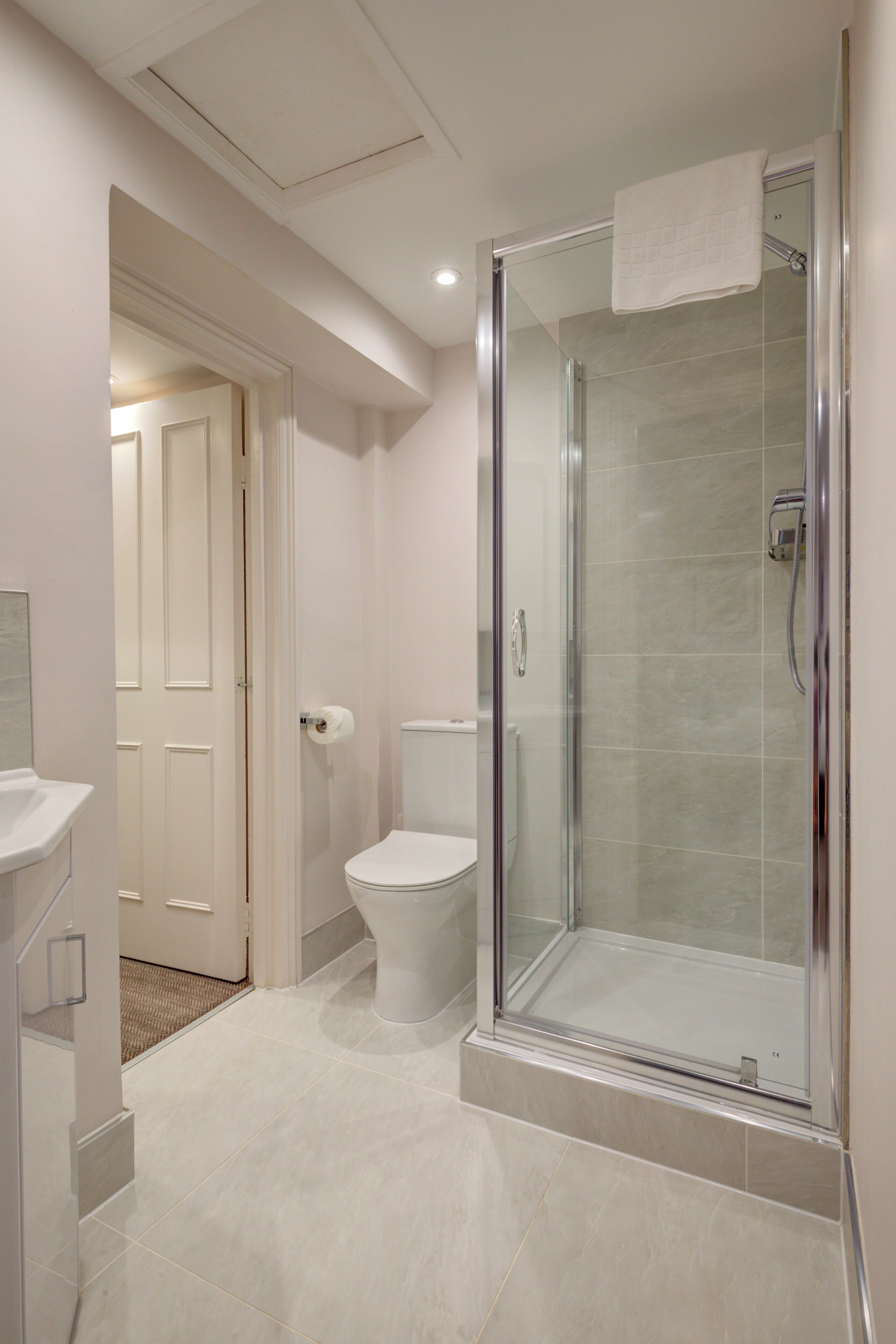A modern bathroom with a glass-enclosed shower, a toilet, and a sink.
