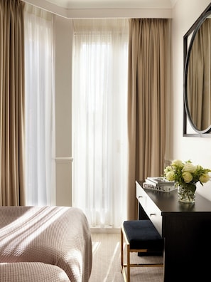 A bedroom with a bed, a desk, a chair, a mirror, and a window with curtains. - Collingham Serviced Apartments (London)