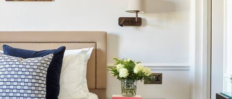 Un dormitorio con cama, mesita de noche, lámpara y un adorno en la pared.