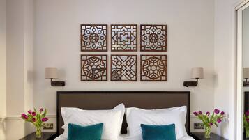A neatly made bed with white and teal pillows, a teal blanket, and decorative wall art above.