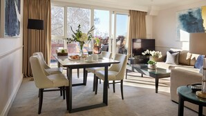 Una sala de estar moderna con comedor, ventanas grandes y un televisor de pantalla plana.