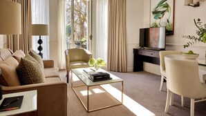 Una sala de estar moderna con un sofá, un sillón, una mesa de centro, un televisor y un escritorio con una silla.