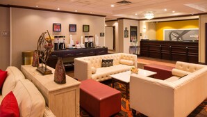 A hotel lobby with a seating area, a reception desk, and a coffee station.