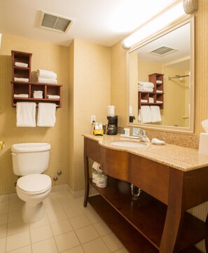 A bathroom with a toilet, sink, and mirror. There are shelves with towels and toiletries. - Hampton Inn by Hilton Toronto-Mississauga West (Mississauga)