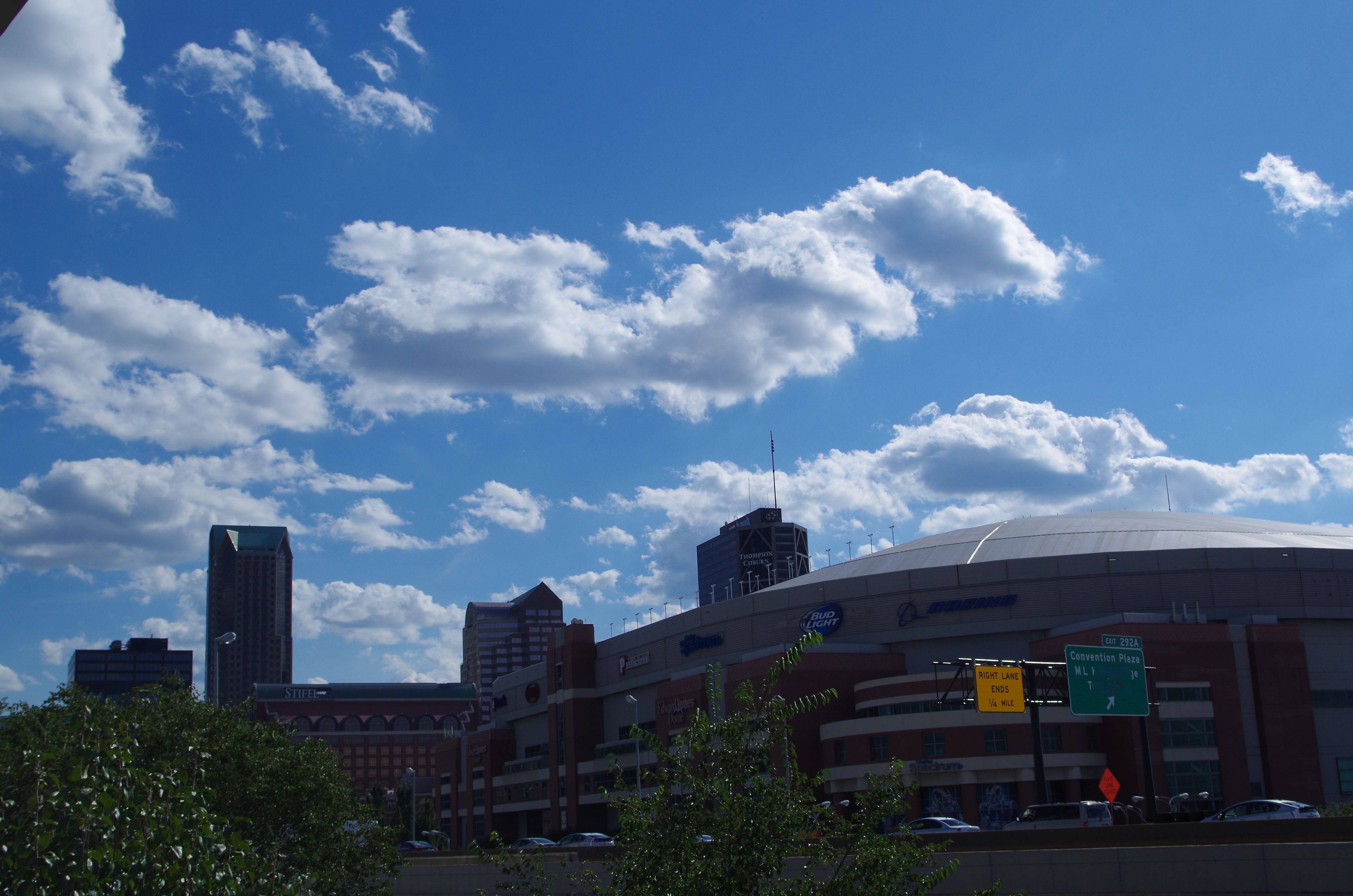 A stadium with a large, curved roof and multiple buildings in the background.