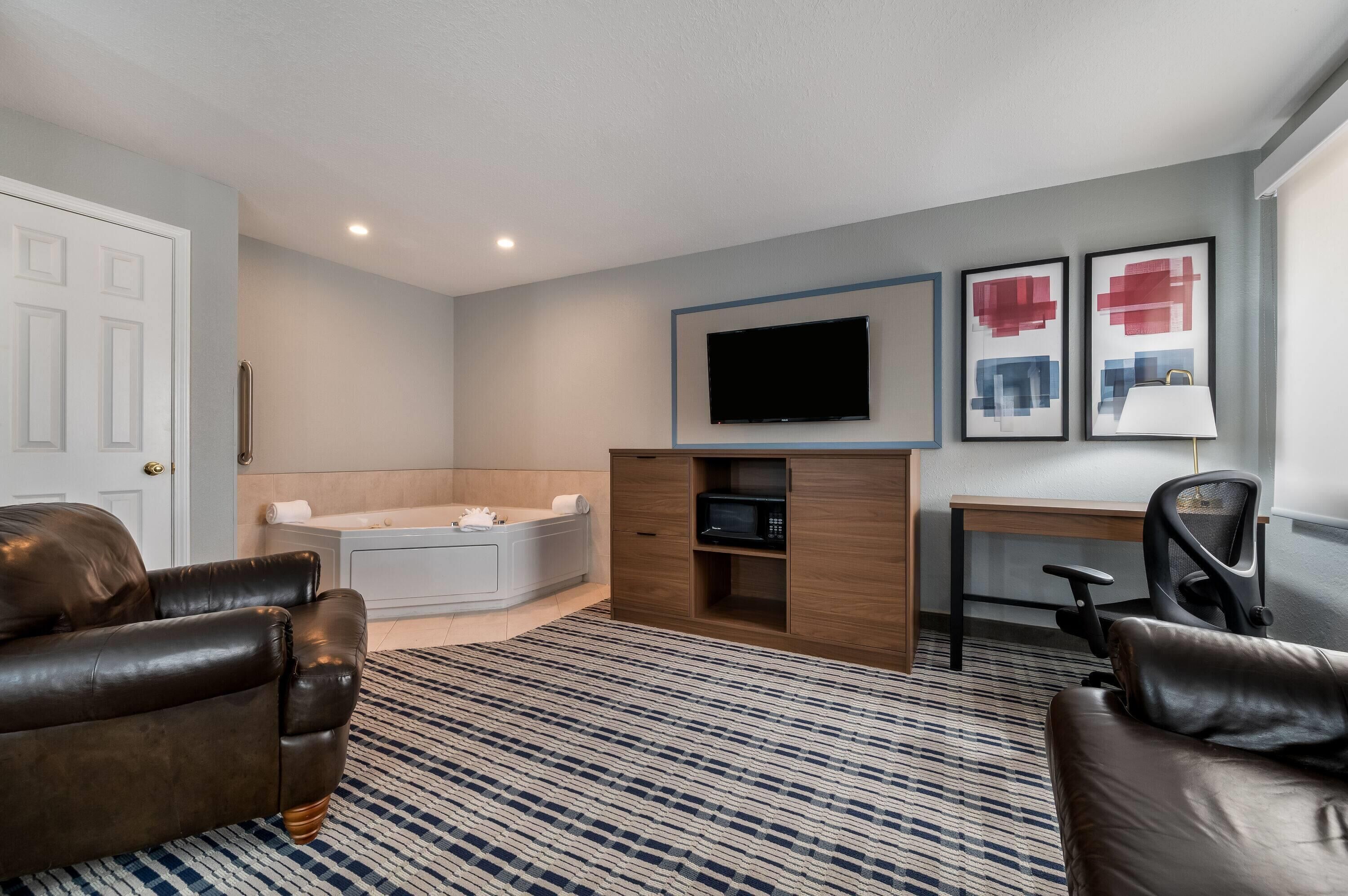 Una habitación moderna con sofá, escritorio, televisor de pantalla plana, sillón de masajes y un mueble pequeño.