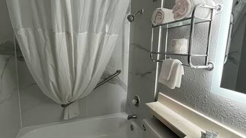 A bathroom with a shower curtain, a glass shower enclosure, a toilet, a sink, and a towel rack with towels.