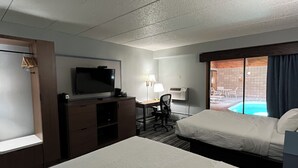 A hotel room with two beds, a desk, a TV, and a view of an outdoor pool. - AmericInn by Wyndham Cloquet (Cloquet)