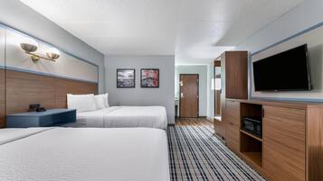 A hotel room with two beds, a flat-screen TV, a desk, and artwork on the wall.