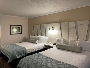 A hotel room with two beds, a nightstand, a framed picture, and a wall-mounted light fixture. - Baechtel Creek Inn (Willits)