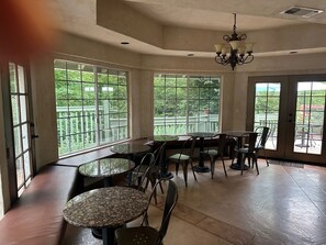 A spacious room with large windows, a chandelier, and multiple seating areas. - Baechtel Creek Inn (Willits)