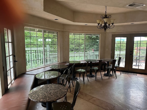 A spacious room with large windows, a chandelier, and multiple seating areas.