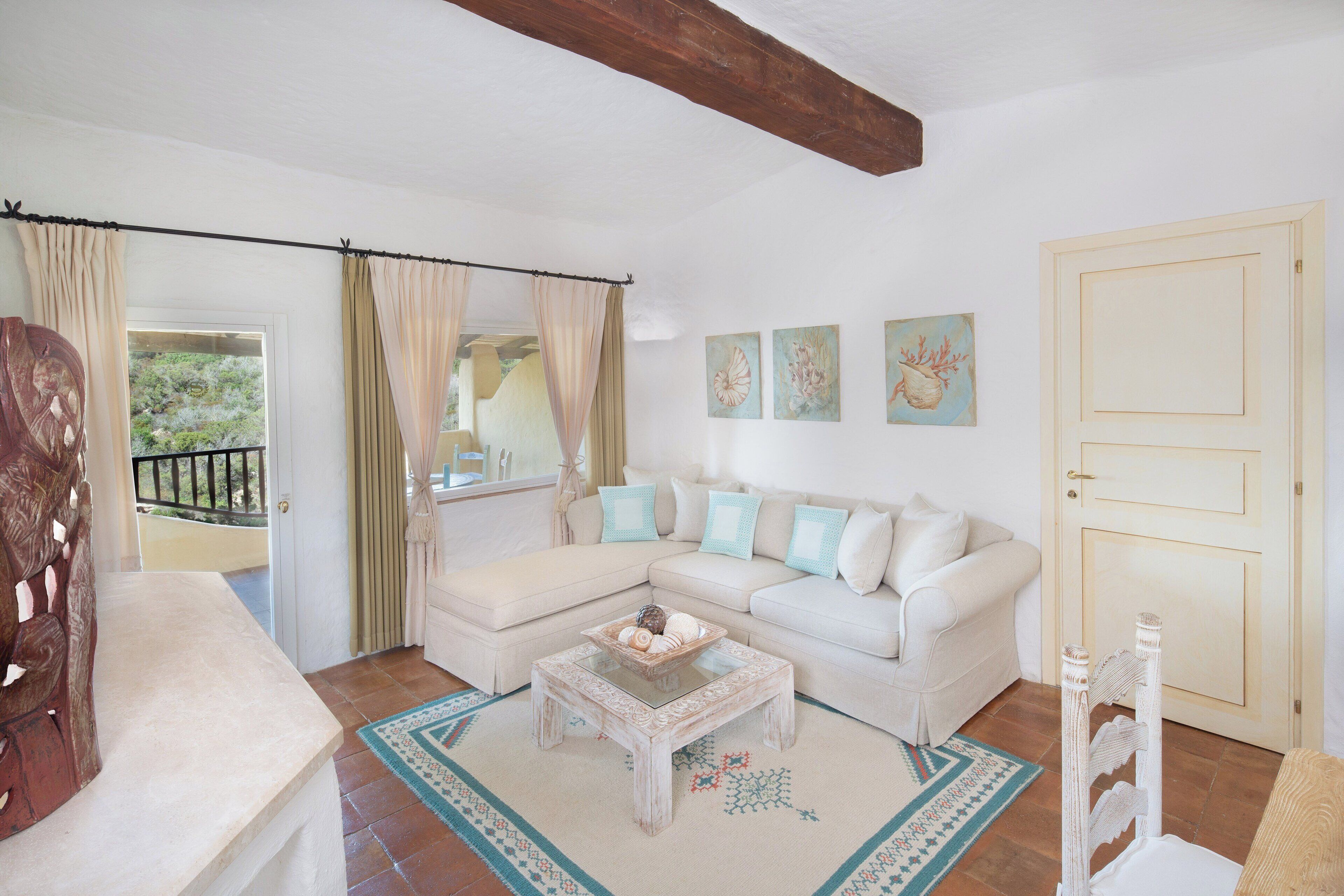 Uma sala de estar com um sofá branco modular, uma mesa de centro de vidro e uma porta de design simples.
