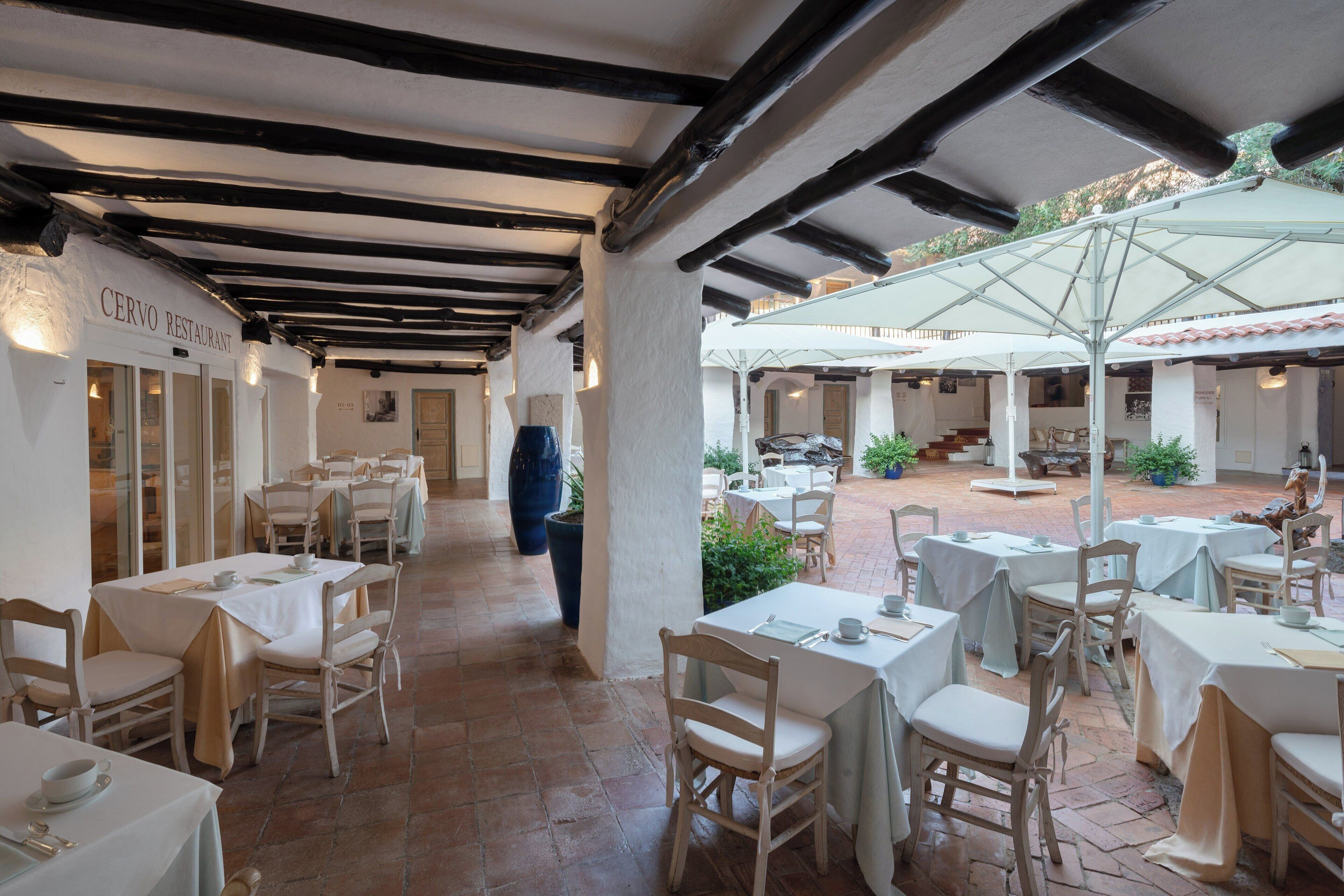 An indoor restaurant with tables and chairs, a sign reading "Cervo Restaurant", and a covered outdoor seating area with umbrellas.
