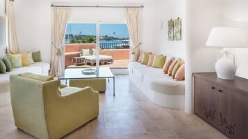 Uma sala de estar moderna com sofá, poltronas, mesa de centro e vista para o mar.