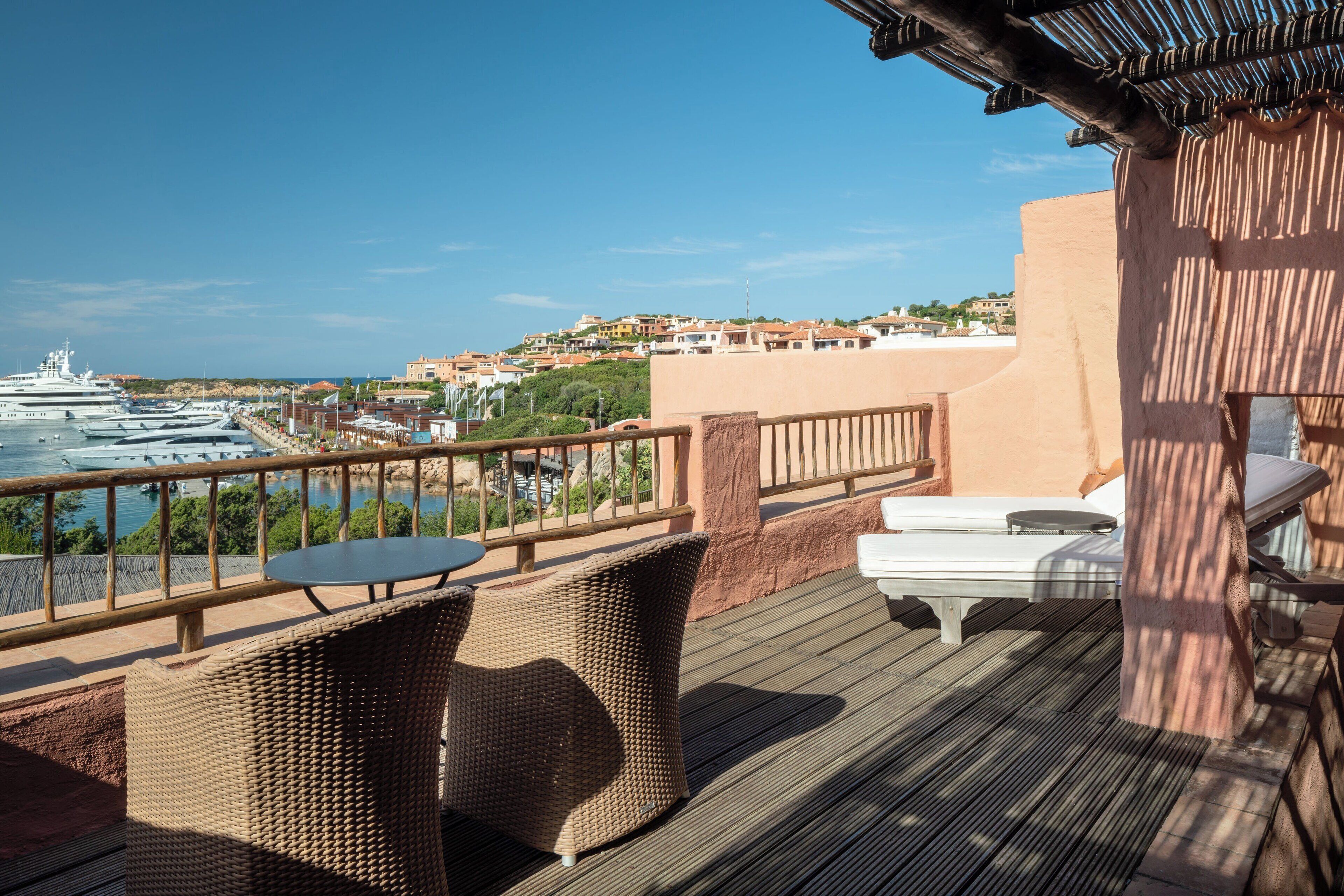 A deck with wicker furniture and a view of a marina with boats.