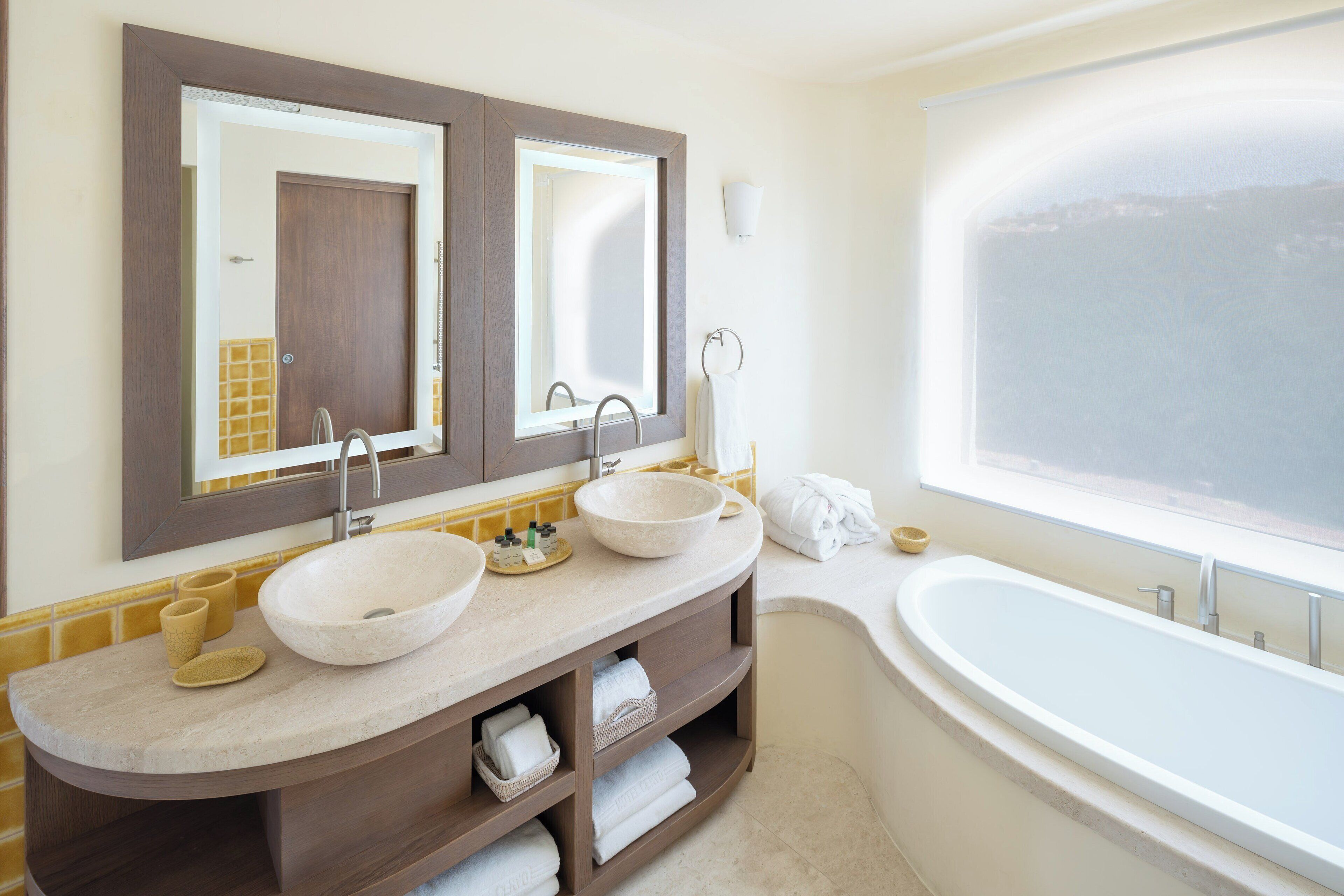 A bathroom with two sinks, a bathtub, and a large mirror.