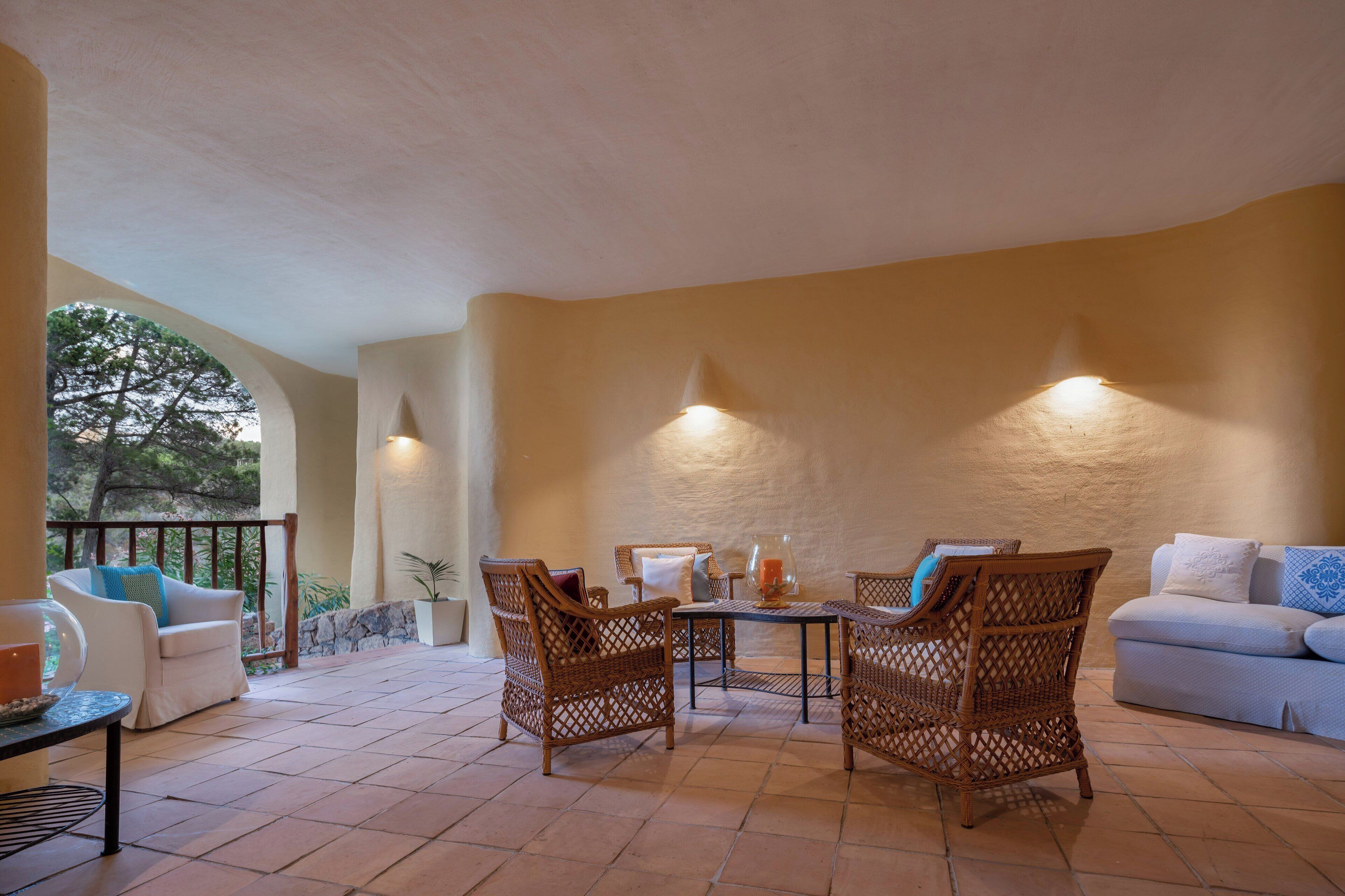 A sunlit patio with wicker furniture, a white sofa, and a glass table.