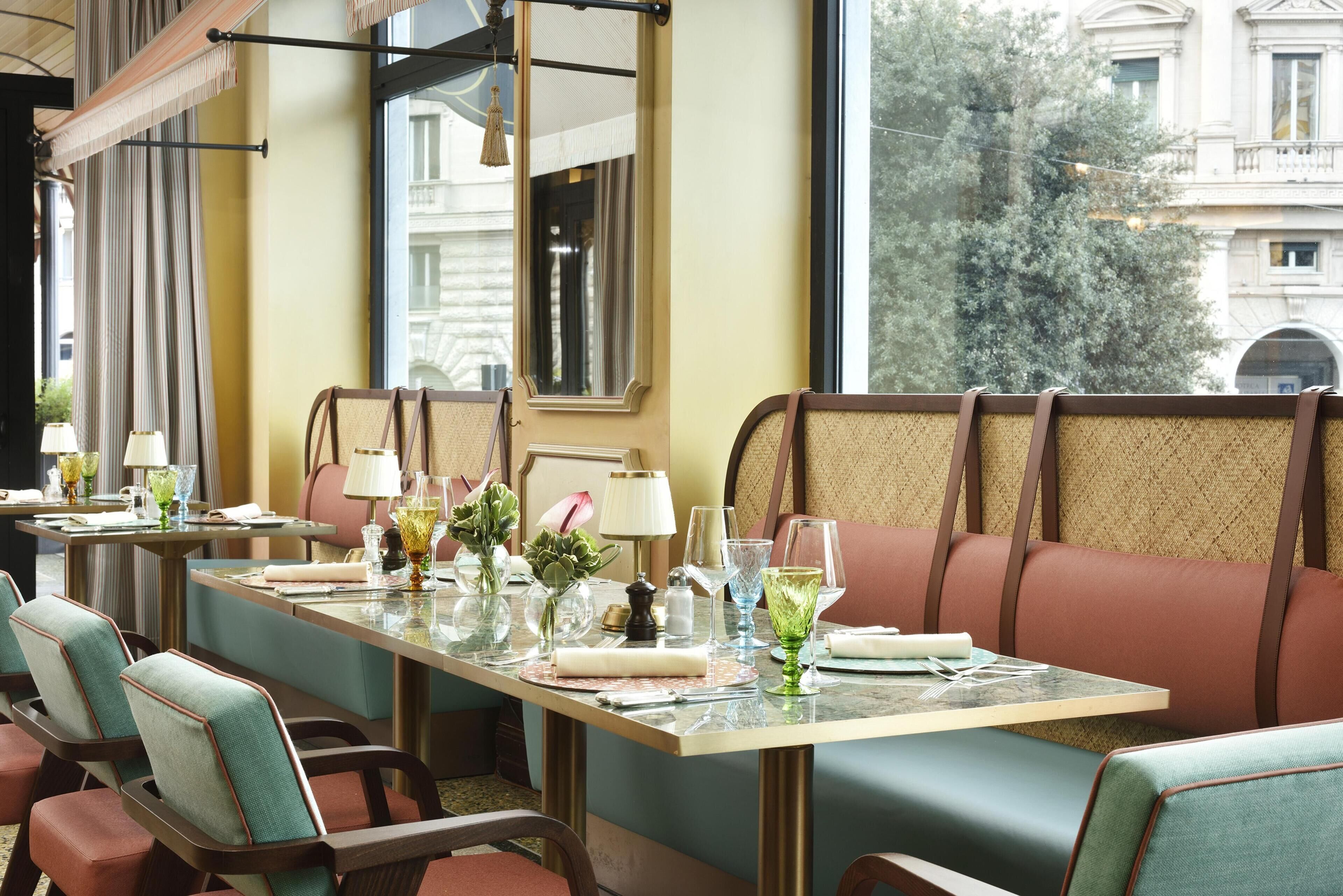 Uma sala de jantar com uma mesa comprida, cadeiras e vista para edifícios.