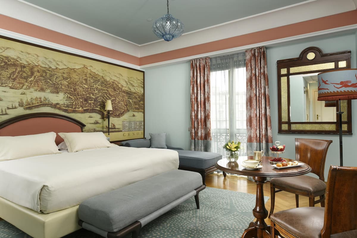 Habitación de hotel con una cama grande, un sofá, una mesa de comedor con un florero y un plato de comida, y un mapa grande en la pared.